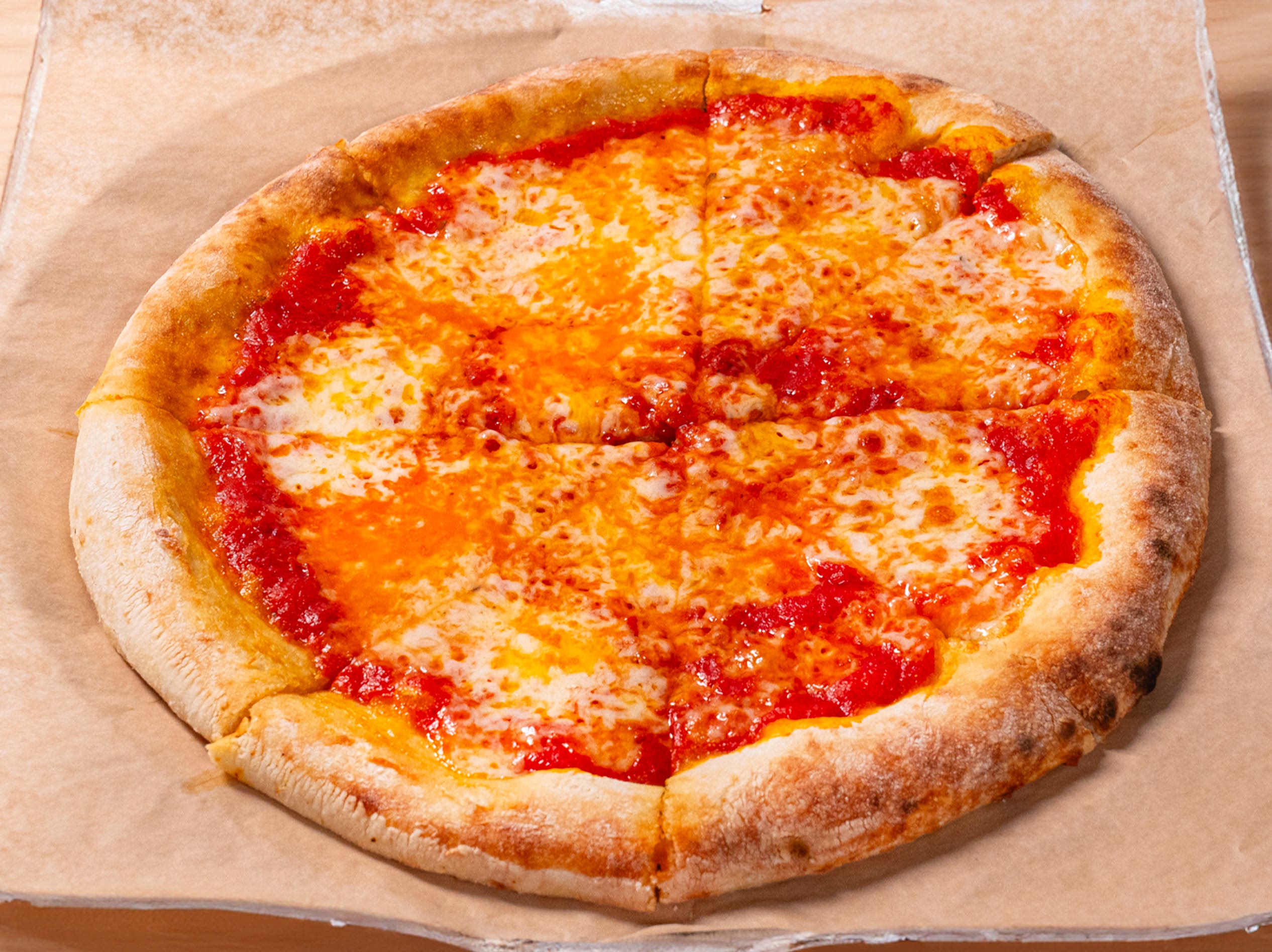 A freshly baked cheese pizza with a golden crust sits in an open cardboard box, ready to be served and enjoyed.
